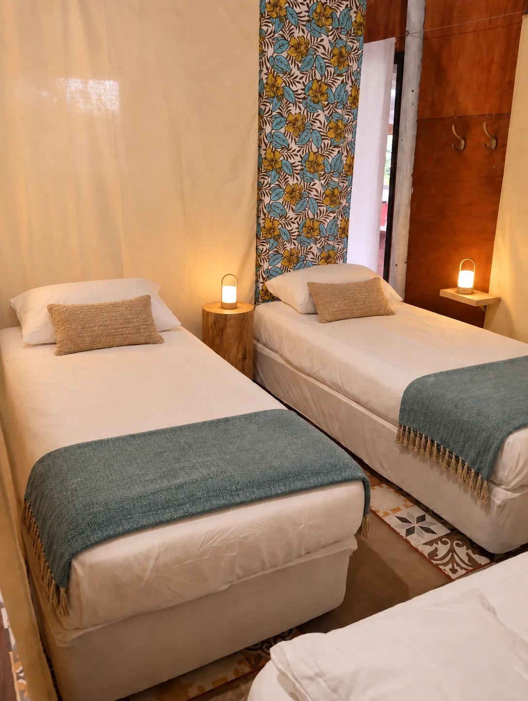 Habitación renovada del Hostel Kona Noho con dos camas individuales, cortina floral y lámparas